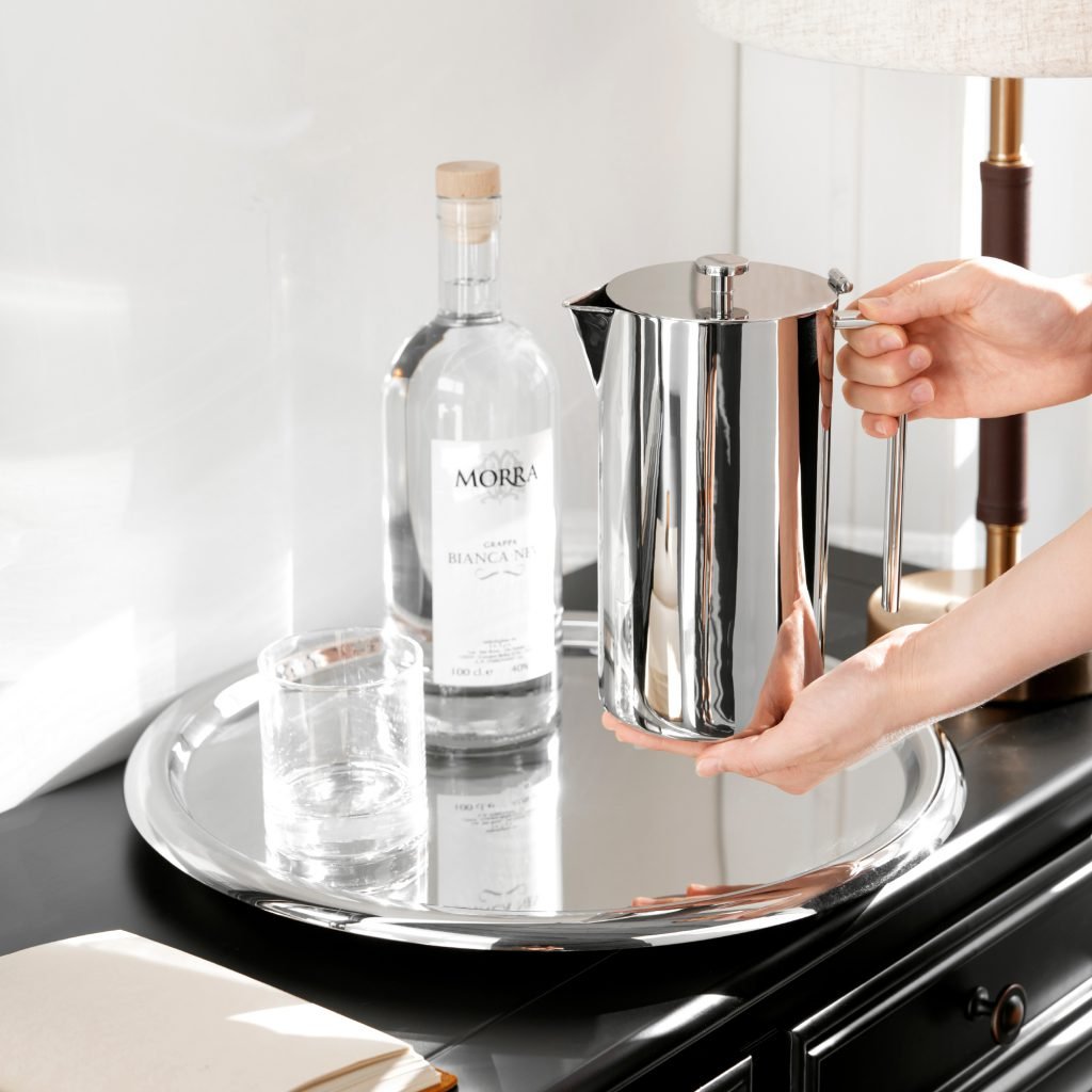Steel Sculptural Pitcher (SS-28) featuring a mirror-polished vertical body and an integrated rectangular geometric handle, showcased as a Luxury Mirror Polished Beverage Carafe.