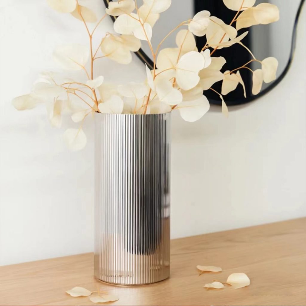 Steel Ribbed Vase (SS-41) featuring a mirror-polished body with vertical fluted textures holding elegant floral stems, showcased as a Luxury Mirror Polished Fluted Vessel.