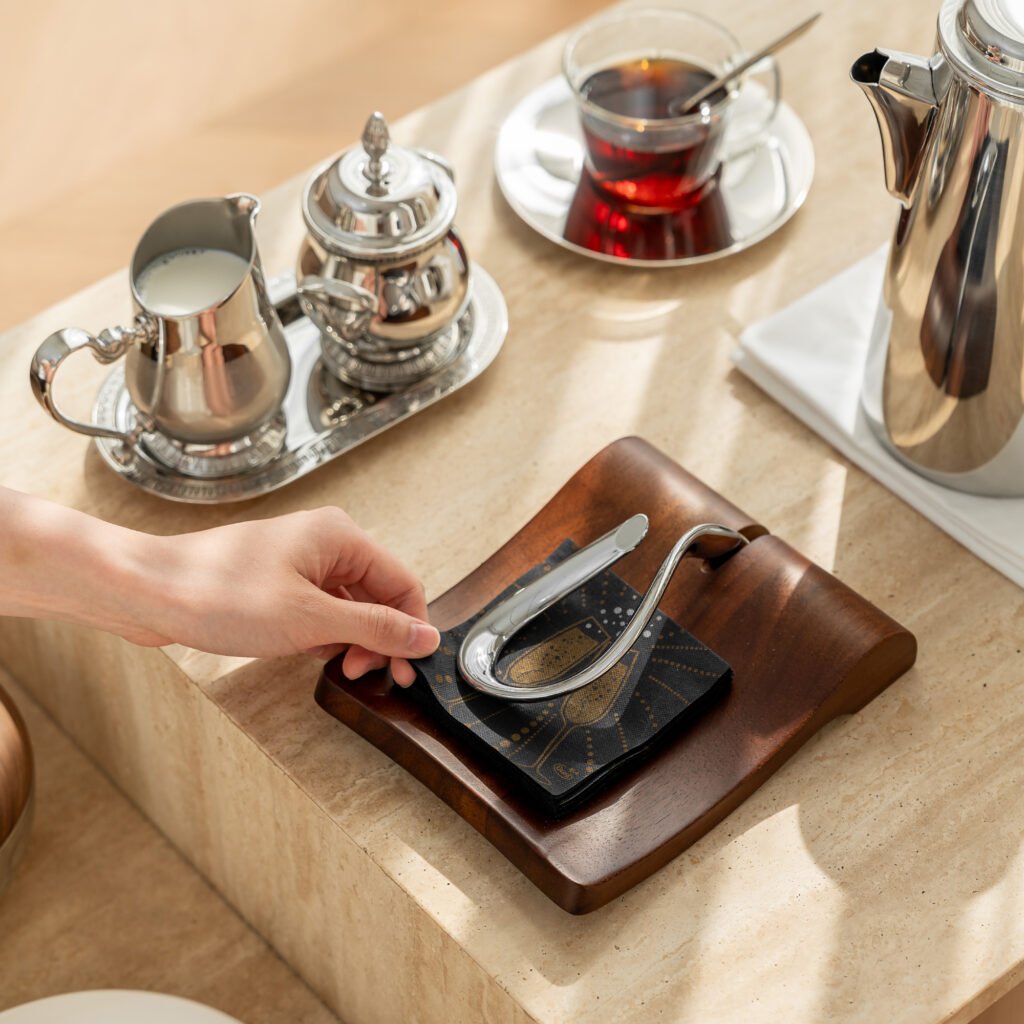 Steel Napkin Tray placed on a teak outdoor table with premium linen napkins, representing Reflective High-End Functional Art elegance.