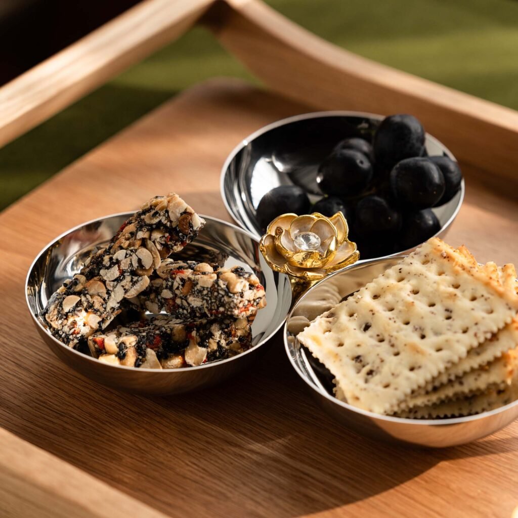 Steel Snack Bowl placed on a dark slate surface with premium nuts, representing Reflective Minimalist Tableware elegance.