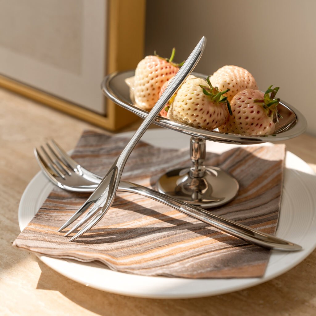 Close-up of the Modernist Metallic Tableware, highlighting the seamless polished finish and the elegant, slender neck of the fork and spoon.