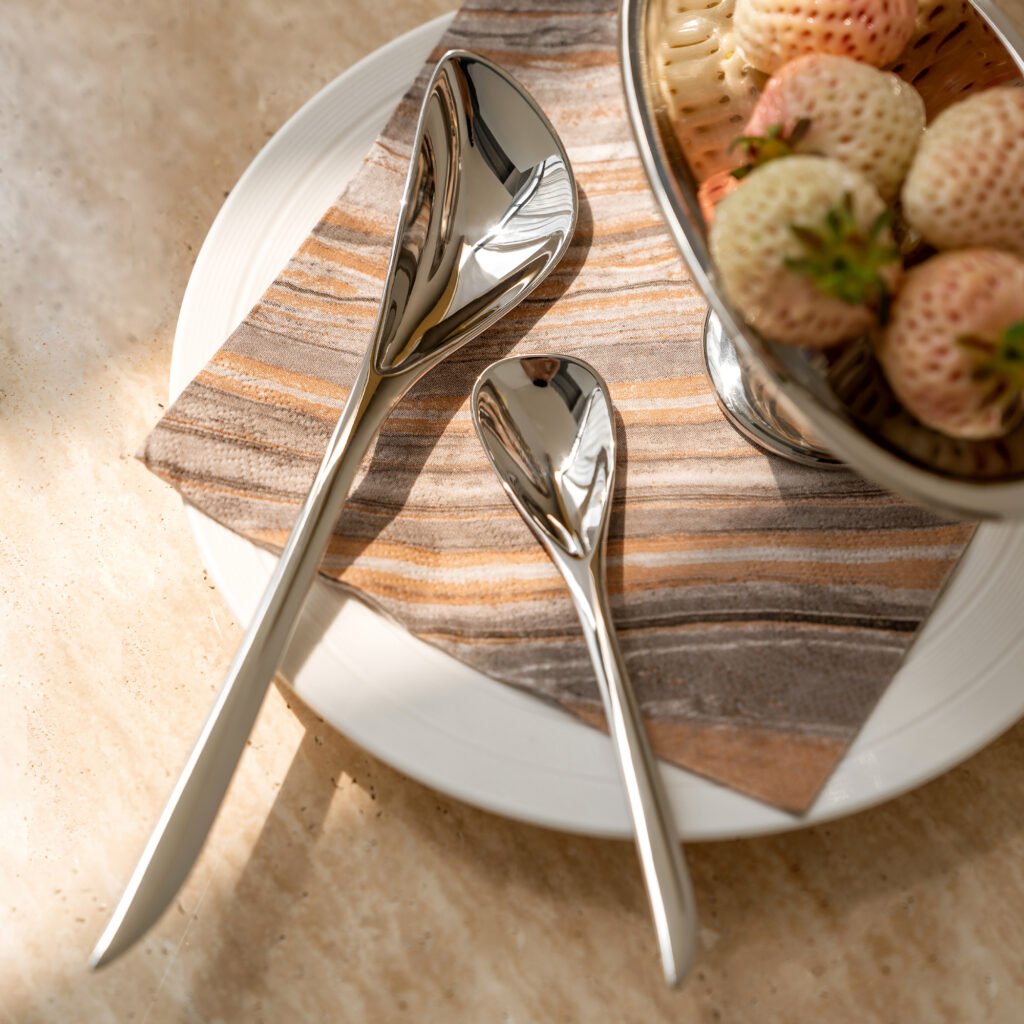 Steel Flatware Set arranged on a dark linen napkin with a minimalist ceramic plate, representing Reflective Minimalist Flatware elegance.