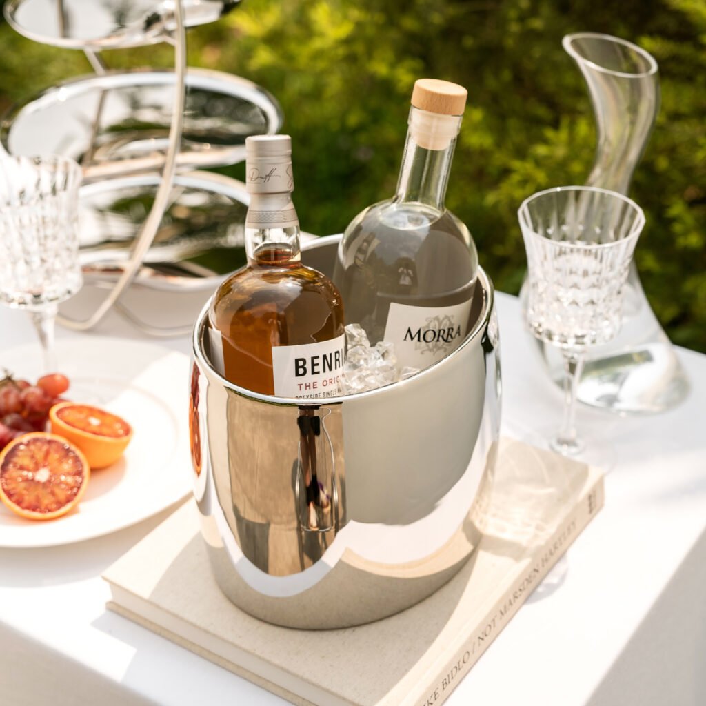 Steel Ice Bucket placed in a modern penthouse bar setting, representing Reflective Modernist Tableware for luxury events.