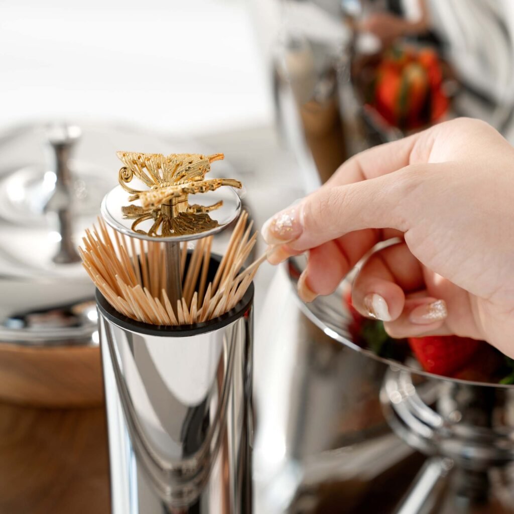 Steel Butterfly Toothpick holder standing on a minimalist white marble surface, representing Reflective Whimsical Dining Art in a luxury setting.