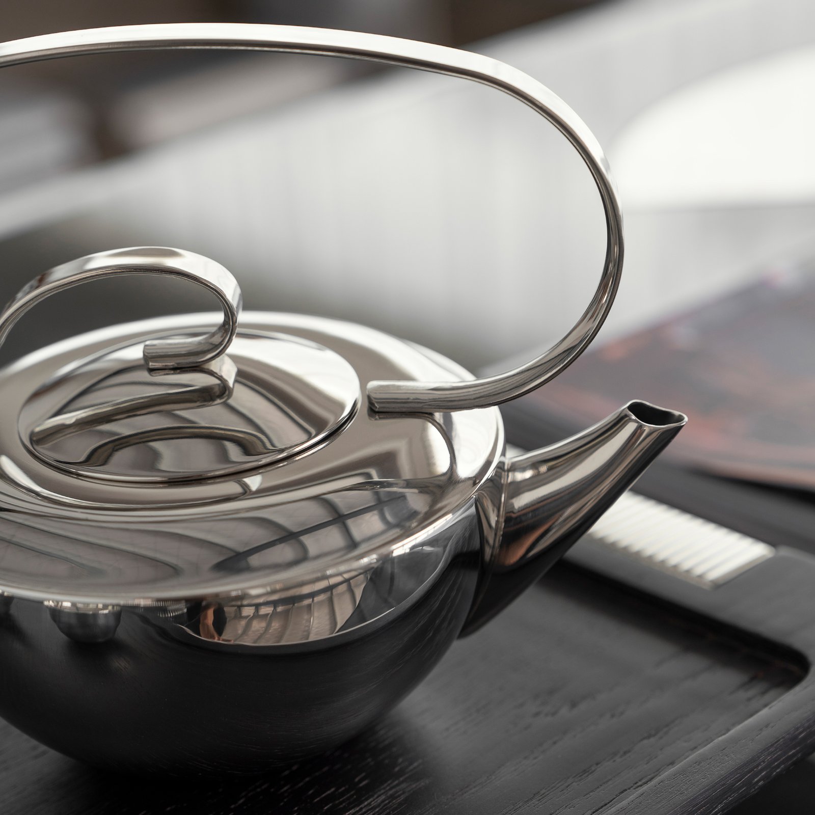Close-up of the Luxury Mirror Polished Tea Pot, highlighting the unique floating geometric handle and the seamless reflective surface.