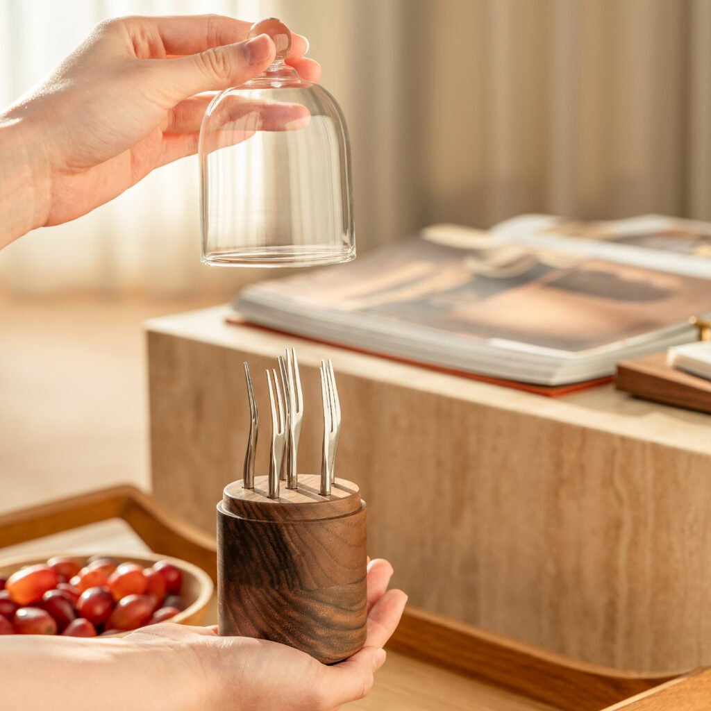 Close-up of the Modernist Glass Dome Metalware, highlighting the precision-weighted base and the flawless, panoramic reflection of the fruit picks inside.
