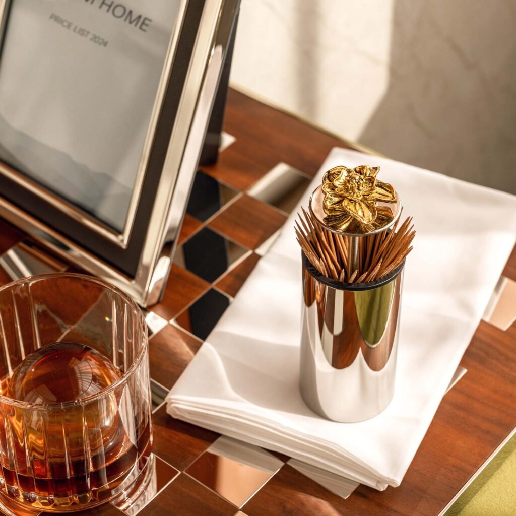 Steel Lotus Toothpick holder standing on a dark stone tea tray, representing Reflective Botanical Dining Art in a luxury setting.