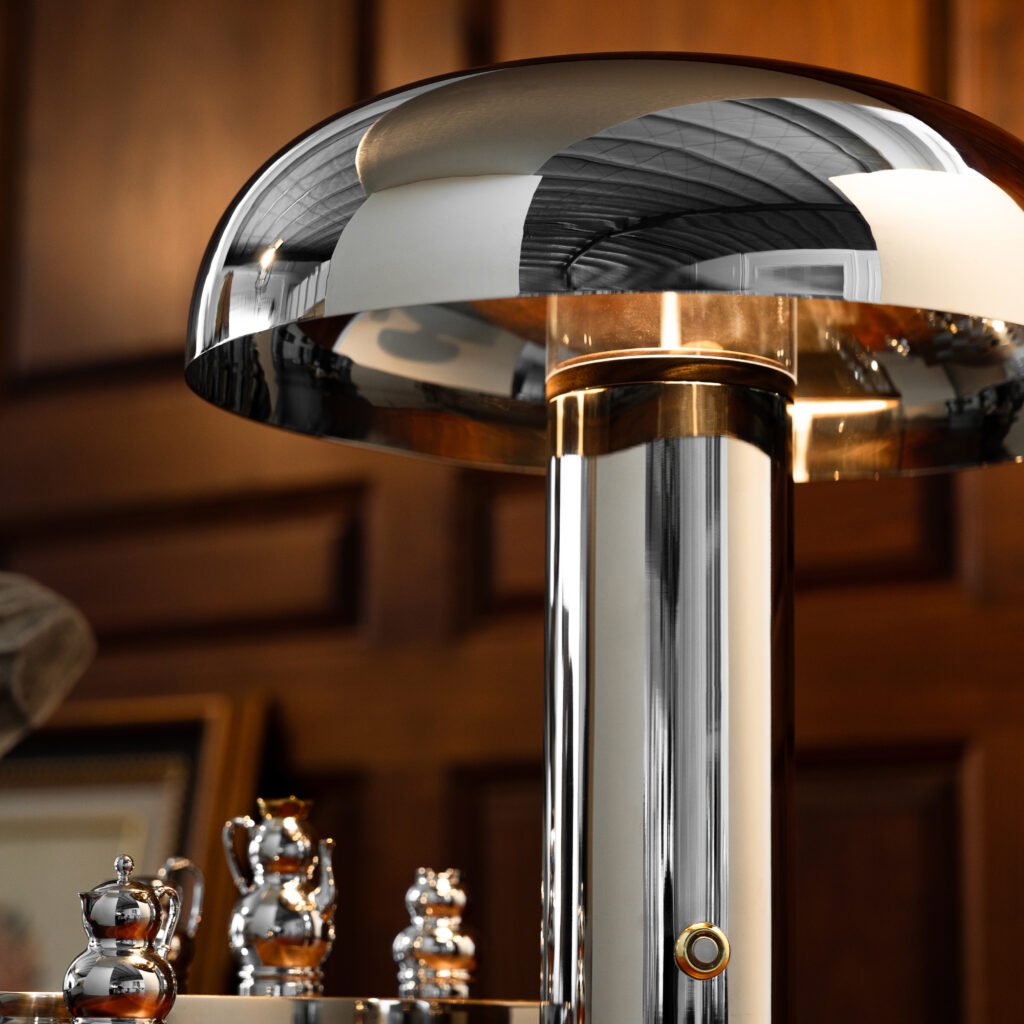 Steel Table Lamp placed on a dark marble nightstand beside a stack of art books, representing Reflective High-End Functional Art elegance.