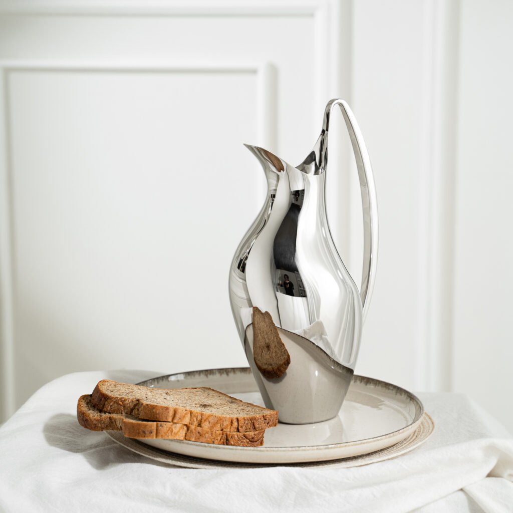 Steel Swan Pitcher (SS-22) featuring a mirror-polished body with a dramatic swan-neck handle and a tapered base, showcased as a Luxury Mirror Polished Serene Server.