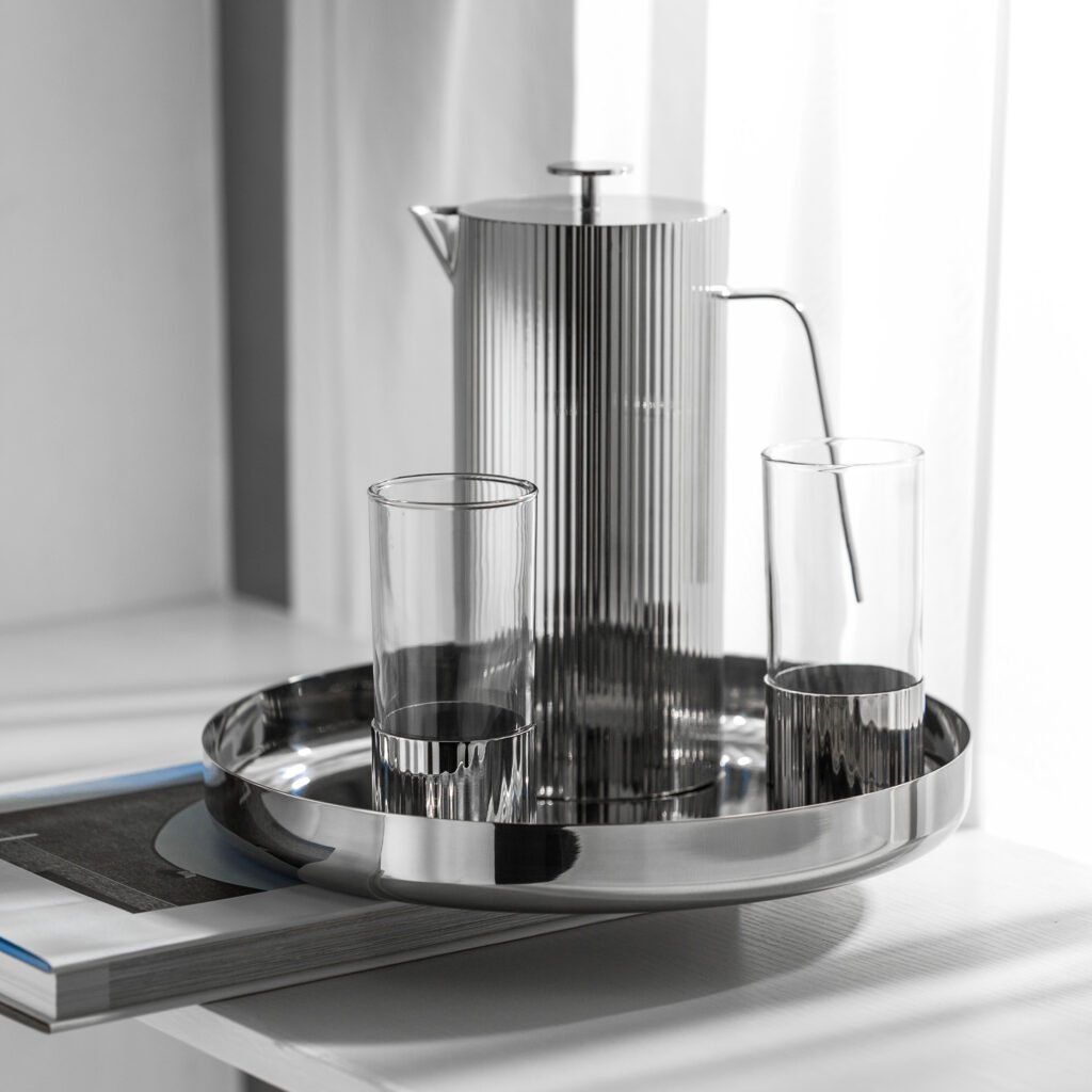 Steel Ribbed Carafe (SS-26) featuring a mirror-polished body with vertical fluted textures and a geometric handle, showcased as a Luxury Mirror Polished Fluted Server.