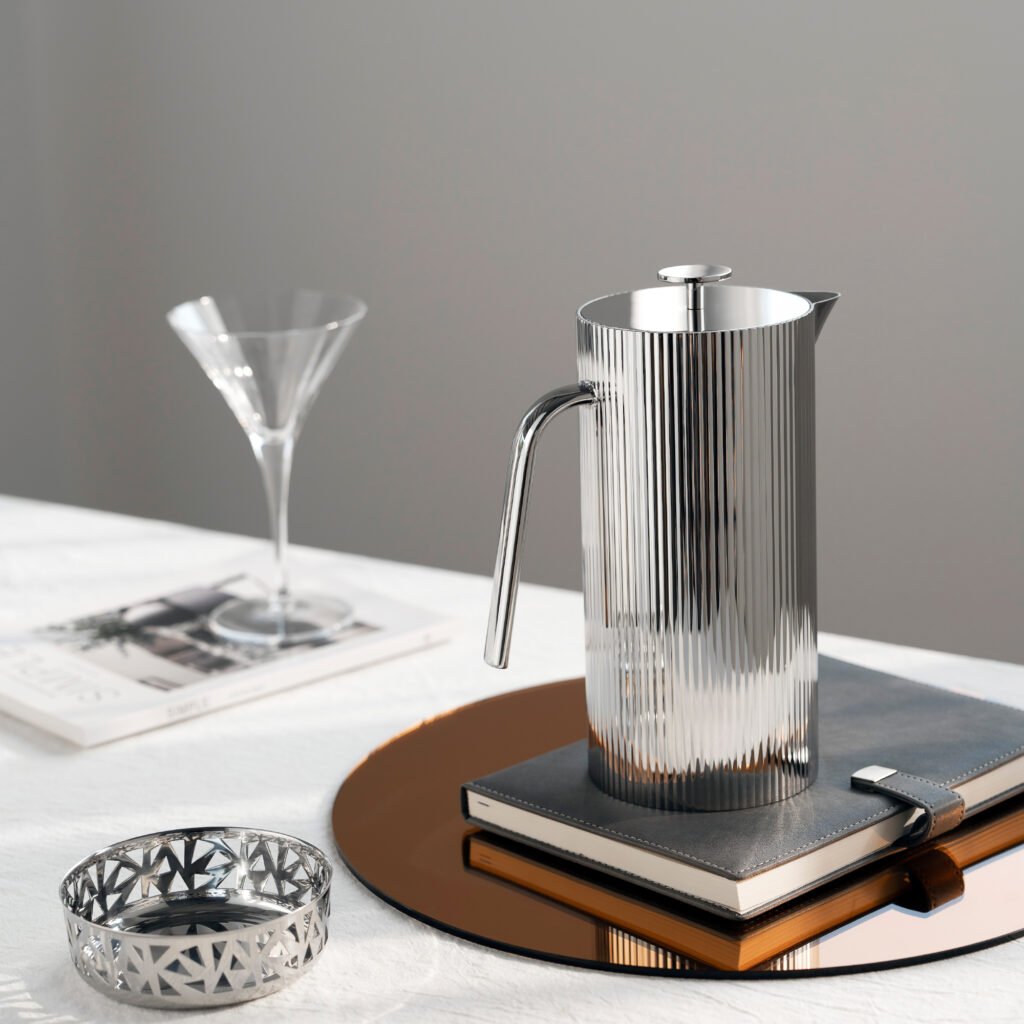 Steel Ribbed Carafe placed on a concrete-textured designer table beside architectural journals, representing Reflective High-End Linear Art elegance.
