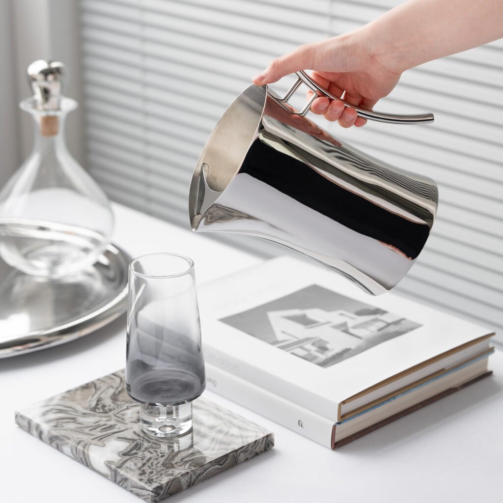 Close-up of the Modernist Conical Metalware, highlighting the precision-poured spout and the flawless, panoramic reflection across the steel surface.