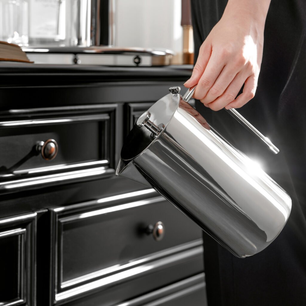 Steel Sculptural Pitcher (SS-28) featuring a mirror-polished vertical body and an integrated rectangular geometric handle, showcased as a Luxury Mirror Polished Beverage Carafe.