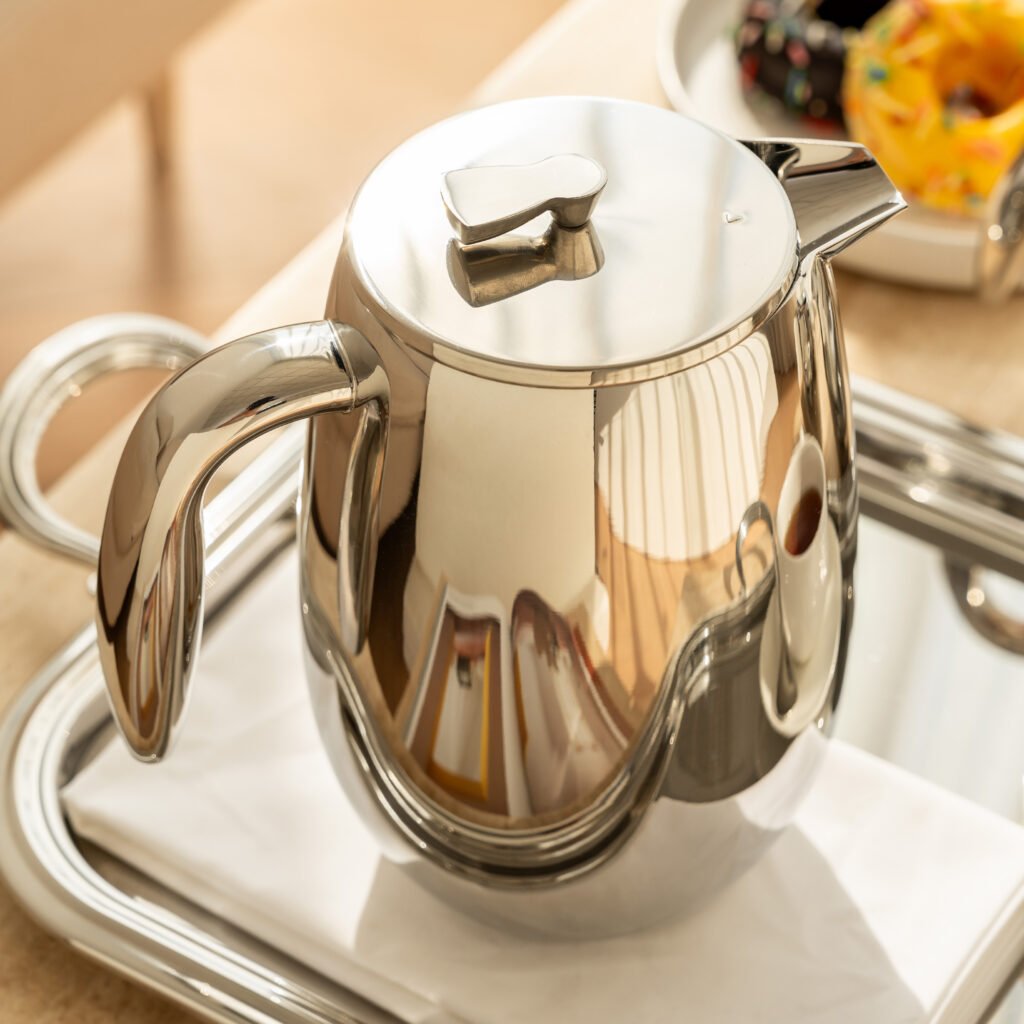 Close-up of the Modernist Aerodynamic Metalware, highlighting the precision-sculpted pouring lip and the flawless, liquid-like reflection across the steel curves.