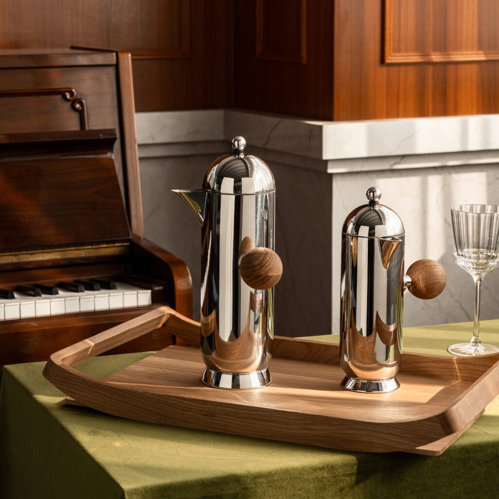 Steel Orb Pitcher (SS-32) featuring a mirror-polished tilted body and a unique spherical handle, showcased as a Luxury Mirror Polished Spherical Server.