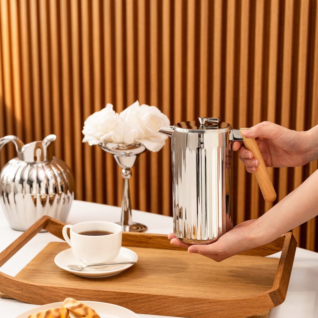 Close-up of the Modernist S-Form Metalware, highlighting the seamless curvature and the liquid-like reflection across the polished steel skin.