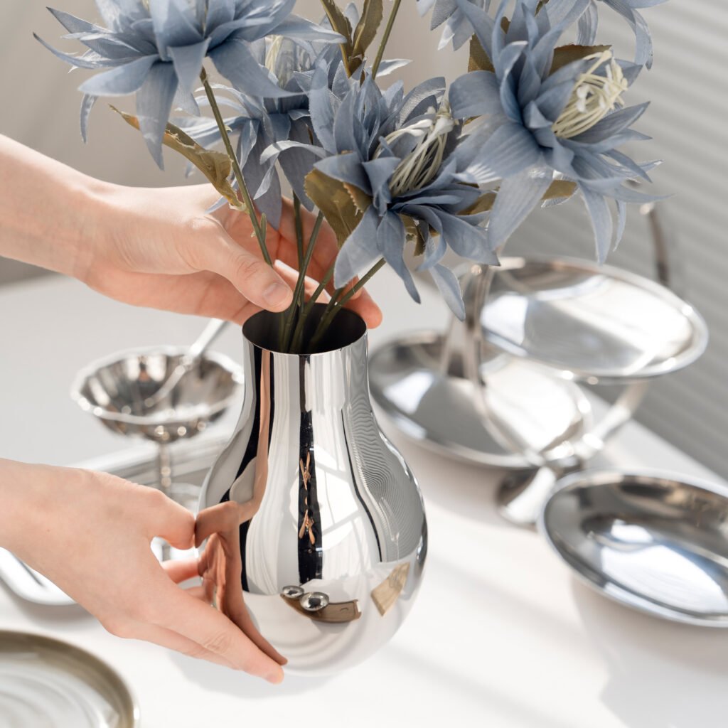 Close-up of the Modernist Bionic Metalware, highlighting the elegant neck curvature and the flawless, panoramic reflective surface of the steel bulb form.