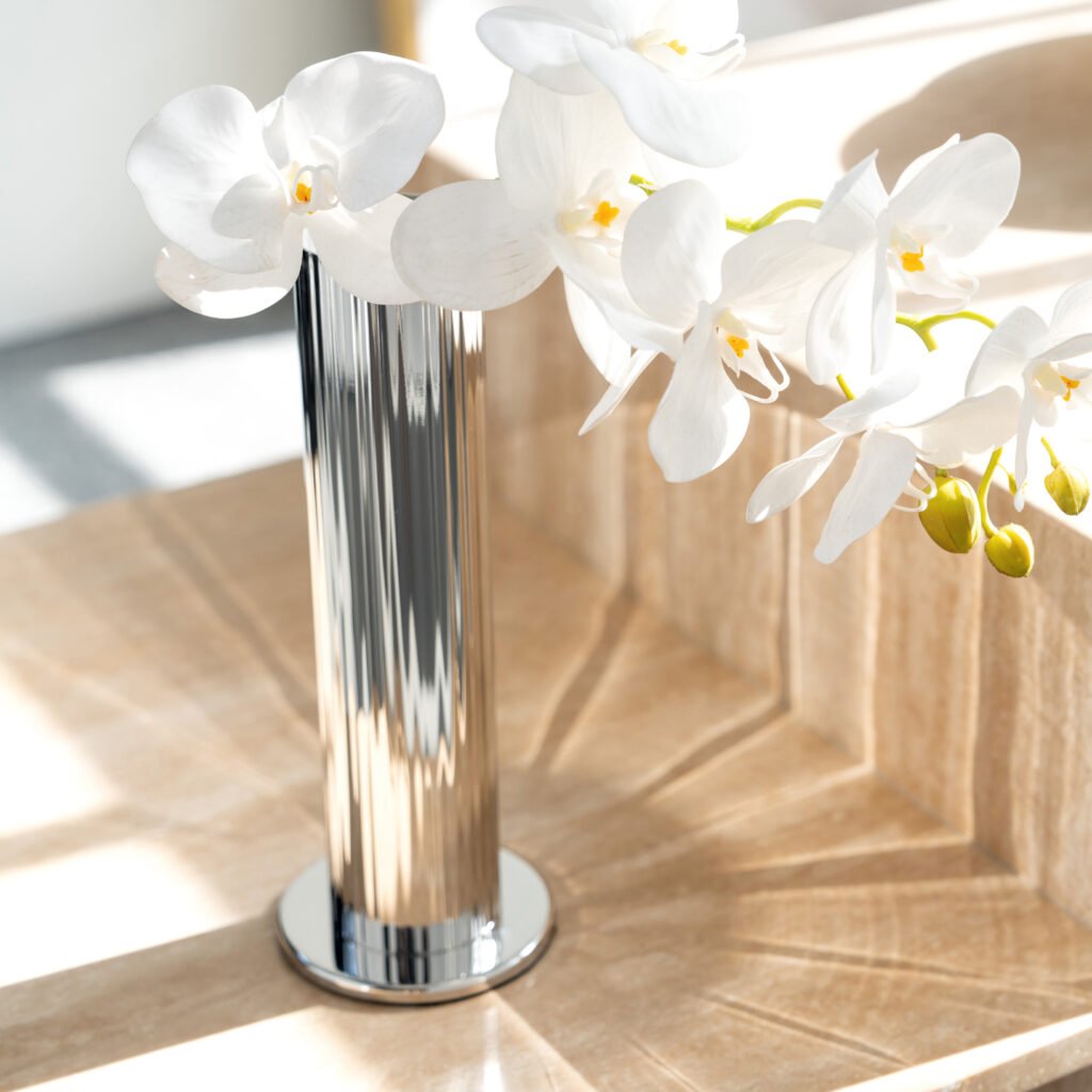 Steel Fluted Vase placed on a minimalist stone pedestal beside architectural sketches, representing Reflective High-End Linear Art elegance.