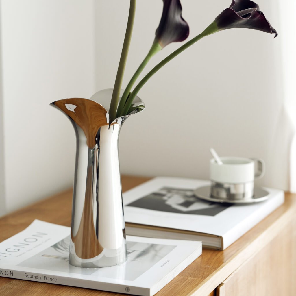 Steel Petal Vase (SS-44) featuring a mirror-polished body with an undulating petal rim holding a single delicate bloom, showcased as a Luxury Mirror Polished Bud Vessel.