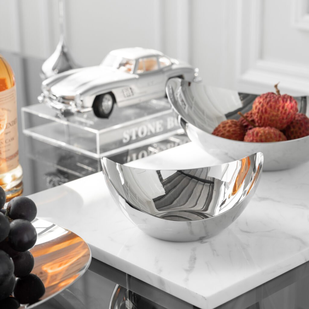 Steel Angled Basin placed on a minimalist dark wood console, filled with vibrant tropical fruits, representing Reflective High-End Display Art.