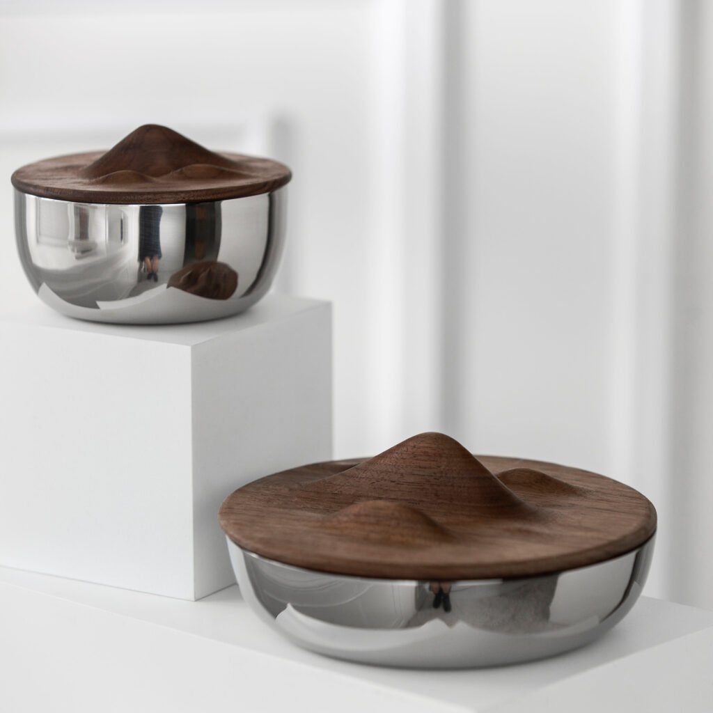 Steel Mountain Bowl placed on a raw stone plinth beside a minimalist carafe, representing Reflective High-End Natural Art elegance.