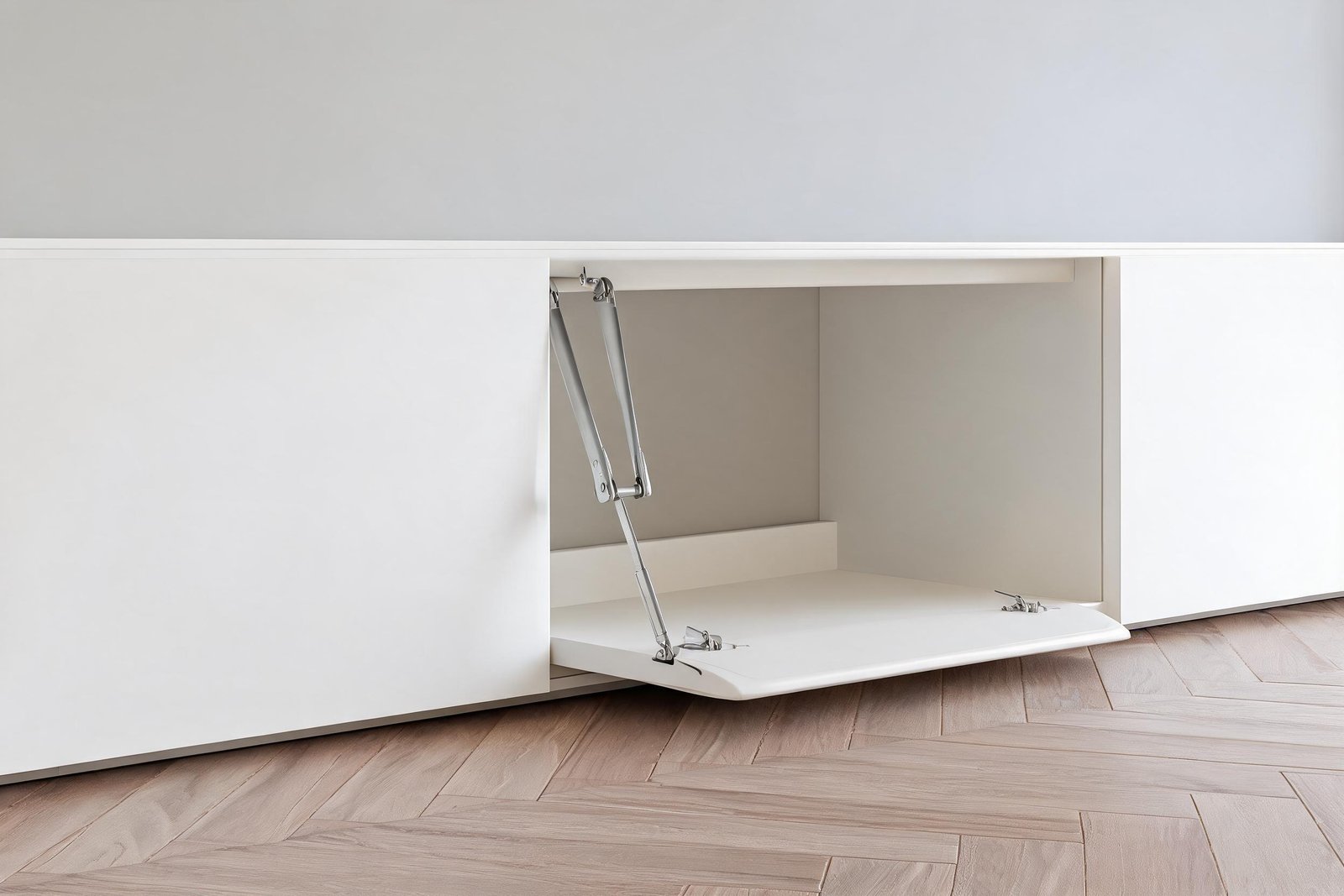 Close-up of a white media console gas strut drop-down door open, showing hidden-handle drawers and soft-close hardware