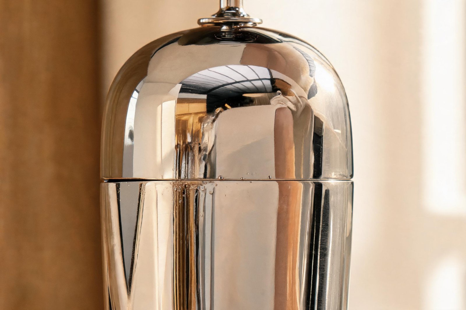 Close view of the cocktail shaker lid stuck seam where the domed cap meets the body on a mirror steel shaker