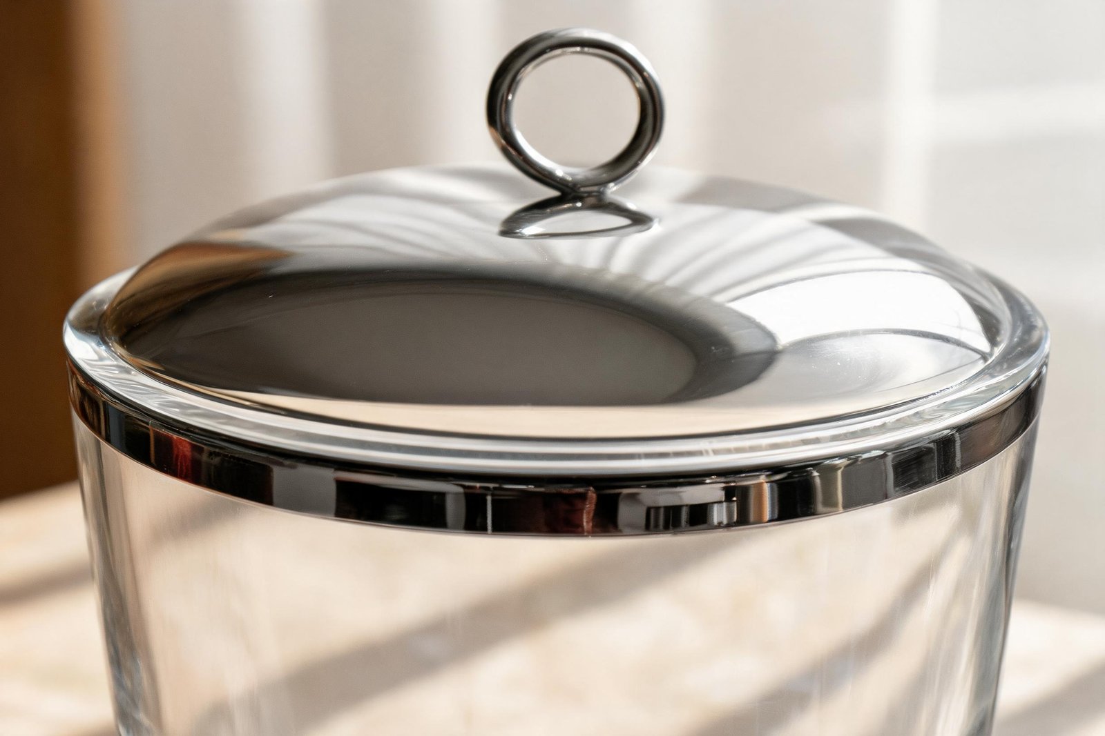 Glass Ice Bucket vs Stainless Steel: What Changes? 2 Macro of a glass ice bucket mouth showing the glass wall thickness, the polished steel band around the outside and the edge of the dome lid resting on it