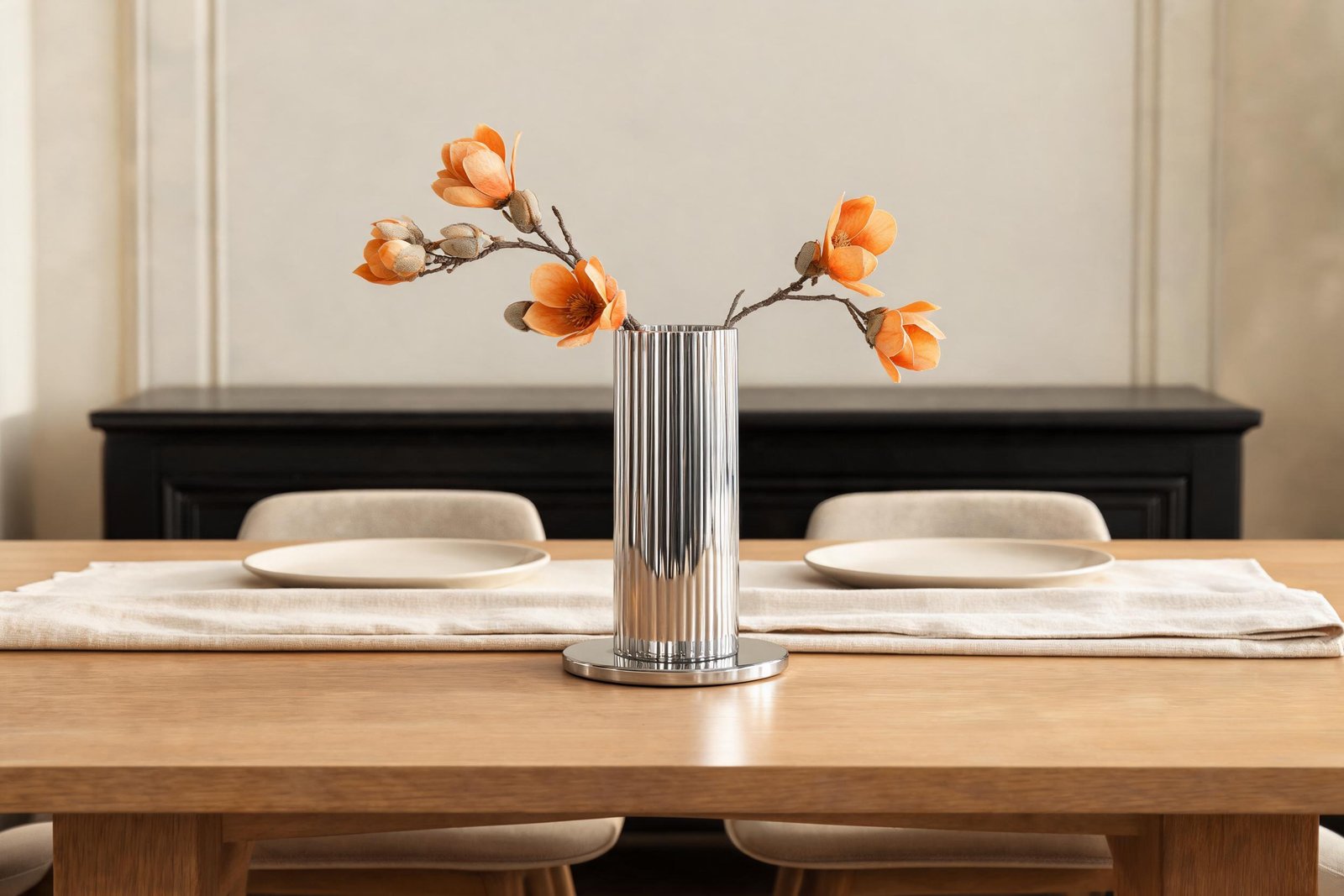 Vase height for dining table rule in practice: a 27 cm fluted mirror steel vase with branches spread low on a pale oak dining table